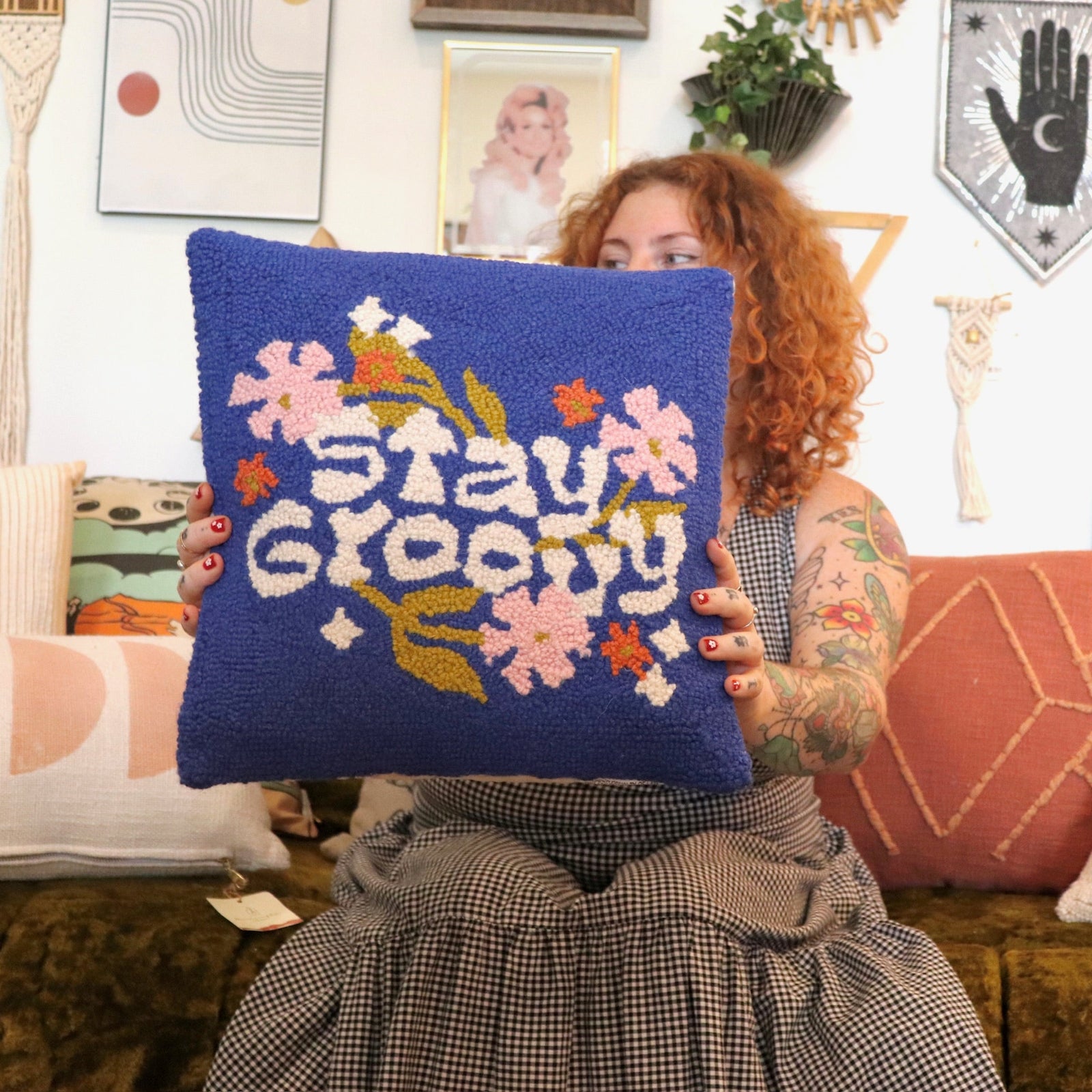 A woman holding the 'Stay Groovy' Wool Hook Pillow.