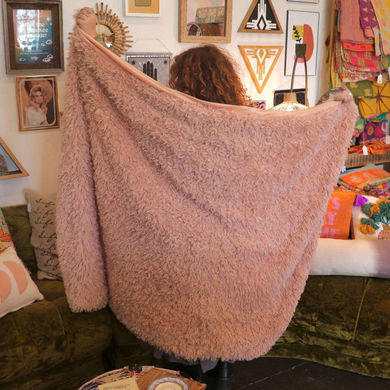 A woman holding the Pink Hero Dreamy Faux Fur Throw Blanket to show off its size.