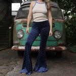 A woman wearing the Navy Velvet Bell Bottom Pants with a cream colored tank all in front of a vintage Volkswagen bus.
