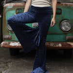 A woman wearing the Navy Velvet Bell Bottom Pants with a cream colored tank all in front of a vintage Volkswagen bus.