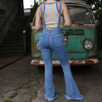 A woman wearing the light denim Bell Bottom Overalls with a cream tank all in front of a vintage Volkswagen bus.
