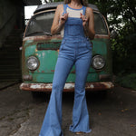 A woman wearing the light denim Bell Bottom Overalls with a cream tank all in front of a vintage Volkswagen bus.