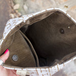 Someone holding the African Off White and Tan Mud Cloth Tote with Pink Faux Fur open to show off its lining and metallic closure.