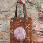 Someone holding the Geometric Rust Mud Cloth Tote with Pink Faux Fur.