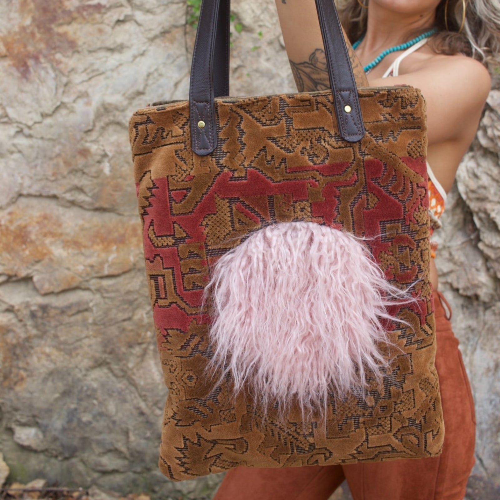 A woman holding the Geometric Velvet Tapestry Tote with Pink Faux Fur.