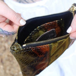 Someone holding the Snake Print Mini Coin Card Pouch open to show the inside.