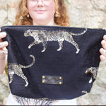 A woman holding the Black Velvet Leopard Traveller Large Pouch.