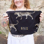 A woman holding the Black Velvet Leopard Traveller Large Pouch.