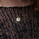 Someone wearing the Capricorn 14k Gold Dipped Nickel-Free Zodiac Necklace with a black net top.