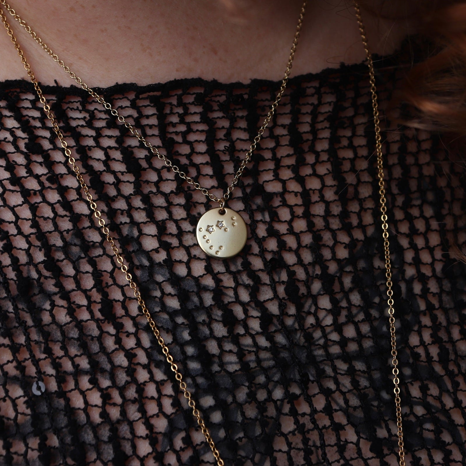 Someone wearing the Capricorn 14k Gold Dipped Nickel-Free Zodiac Necklace with a black net top.