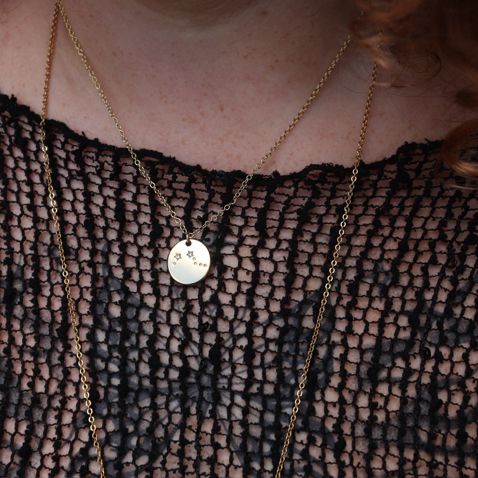 Someone wearing the Aries 14k Gold Dipped Nickel-Free Zodiac Necklace with a black net top.