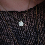 Someone wearing the Gemini 14k Gold Dipped Nickel-Free Zodiac Necklace with a black net top.