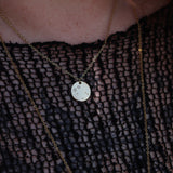 Someone wearing the Gemini 14k Gold Dipped Nickel-Free Zodiac Necklace with a black net top.