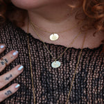 A woman wearing two of the 14k Gold Dipped Nickel-Free Birth Month Flower Necklaces with a black mesh top.