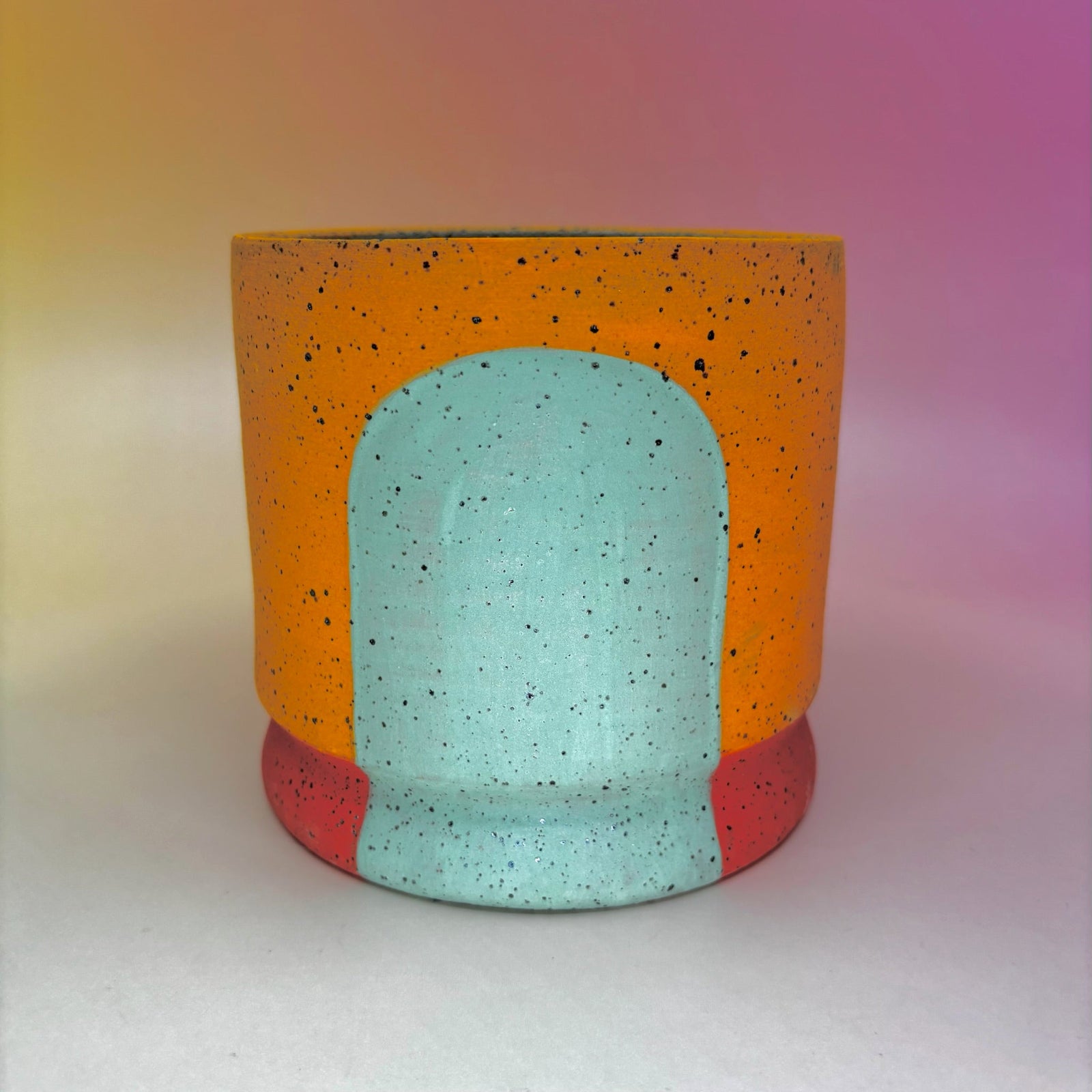 The Phoebe Multicolored Portal Stoneware 5 in. Planter on a pink and yellow background.