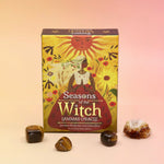 The Lammas Oracle Card Deck surrounded by tumbled crystals on a pink and yellow background.