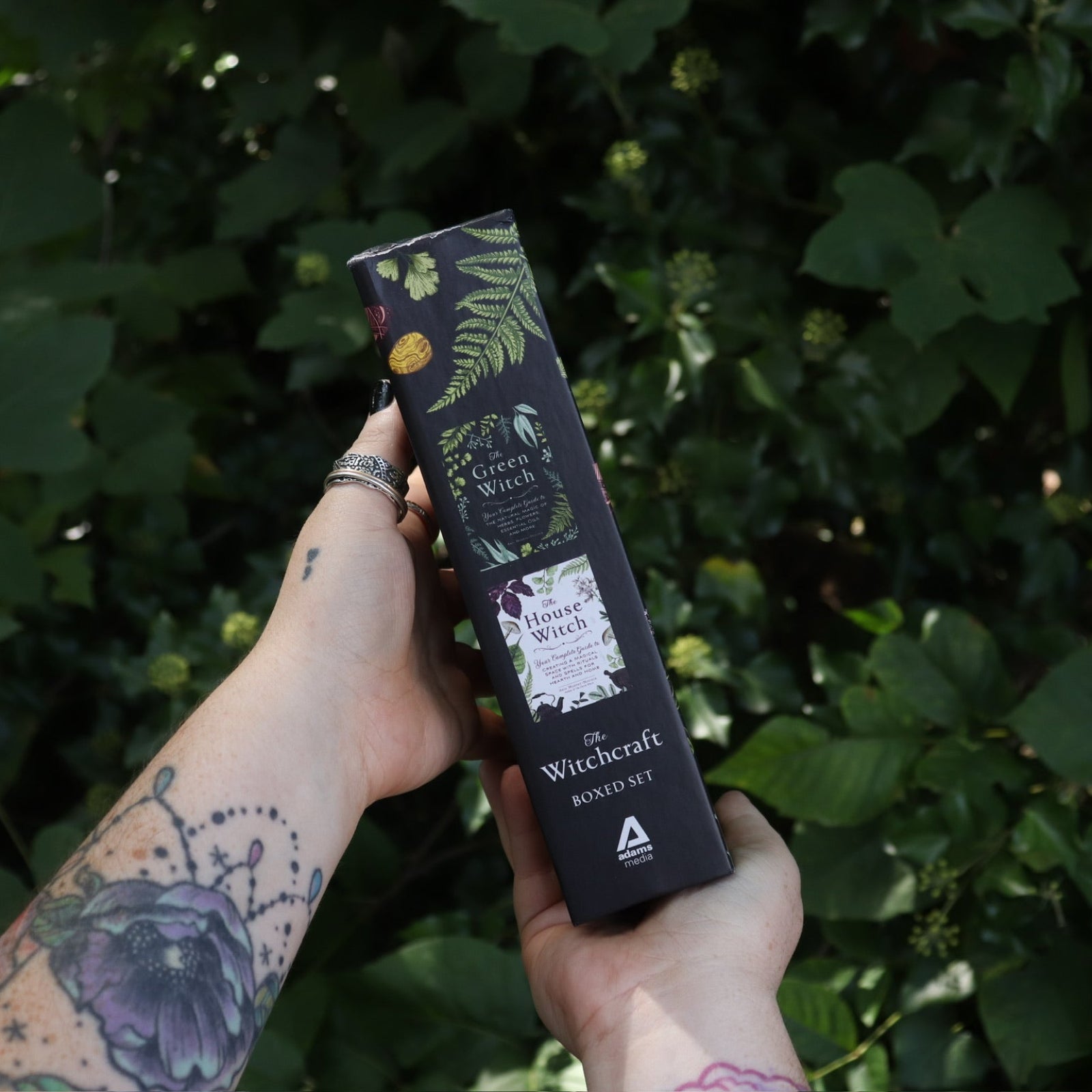 Someone holding the Witchcraft Boxed Set by Arin Murphy-Hiscock in front of greenery showing the side of the set.