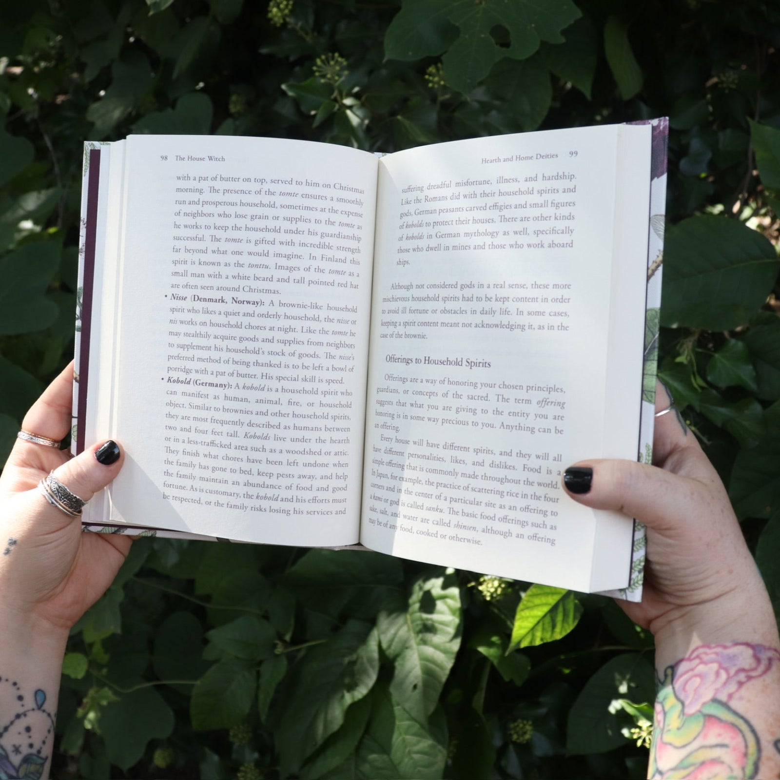 Someone holding one of the books open from the Witchcraft Boxed Set by Arin Murphy-Hiscock in front of greenery.
