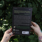Someone holding Runes for the Green Witch by Nicolette Miele in front of greenery showing off the back.