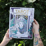 Someone holding the Tarot Coloring - Coloring Book in front of greenery.