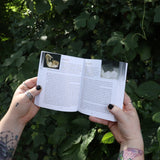 Someone holding the Pocket Book of Stones by Robert Simmons open in front of greenery to show off its pages.