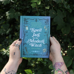 Someone holding the Spell Jars for the Modern Witch Book in front of greenery.