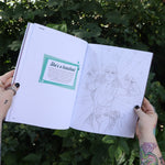 Someone holding the Chappell Roan Coloring & Activity Book open in front of greenery, showing off the pages.
