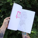 Someone holding the Chappell Roan Coloring & Activity Book open in front of greenery, showing off the pages.