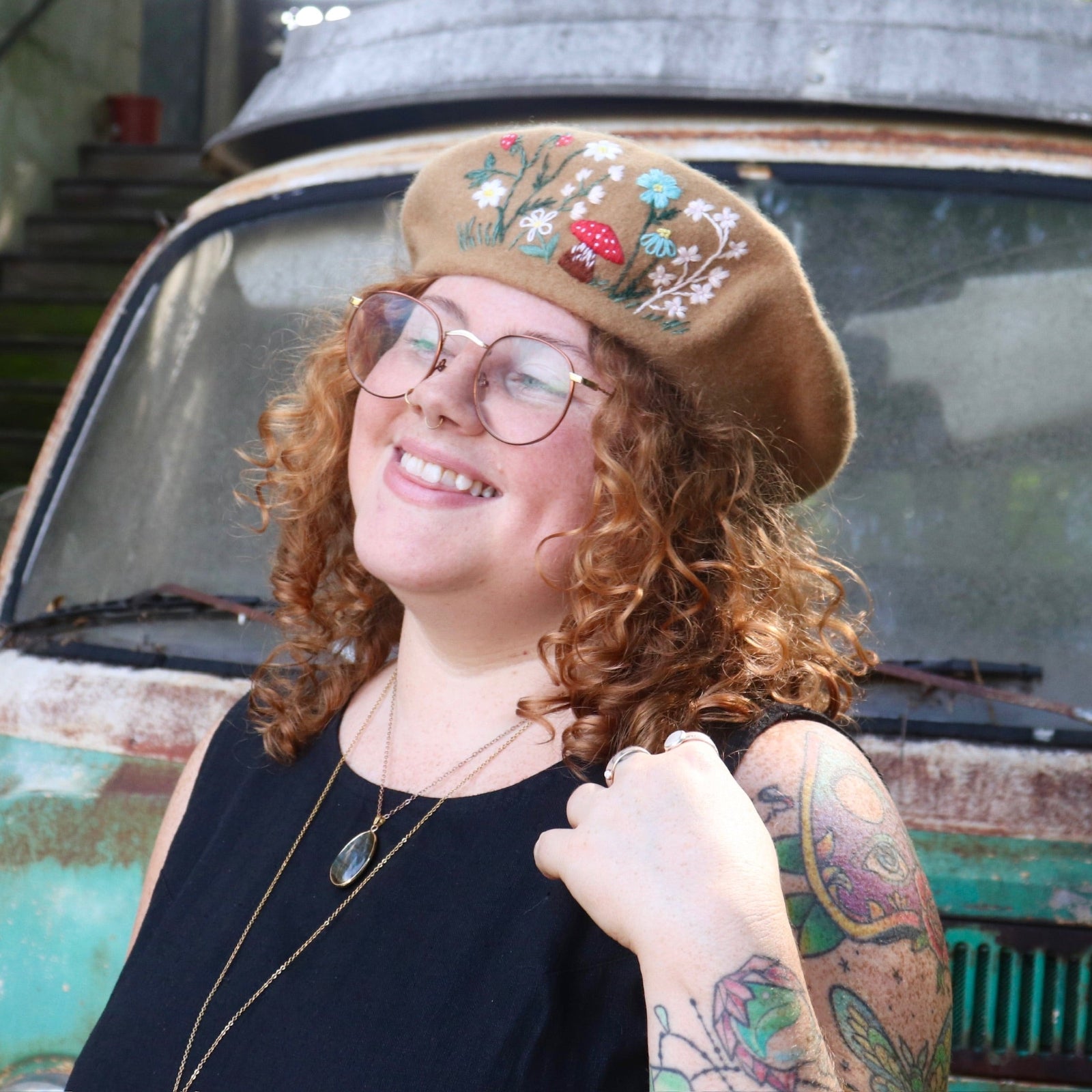 A woman wearing the beige Hand-Embroidered Floral Soft Beret Stylish Hat with a black shirt.