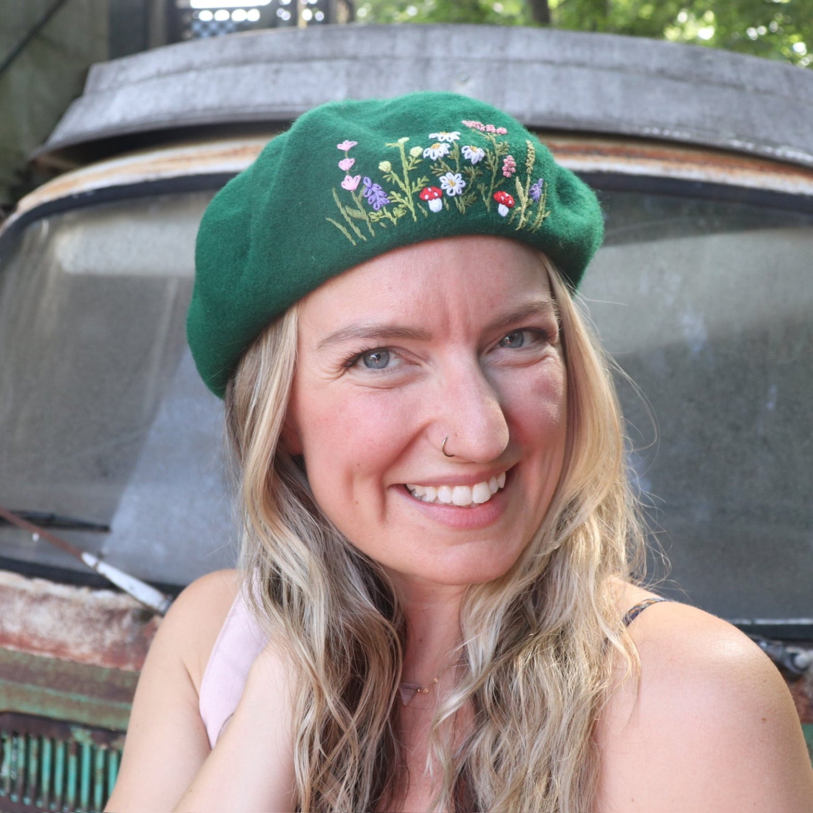 A woman wearing the green Hand-Embroidered Floral Soft Beret Stylish Hat with a navy floral dress.
