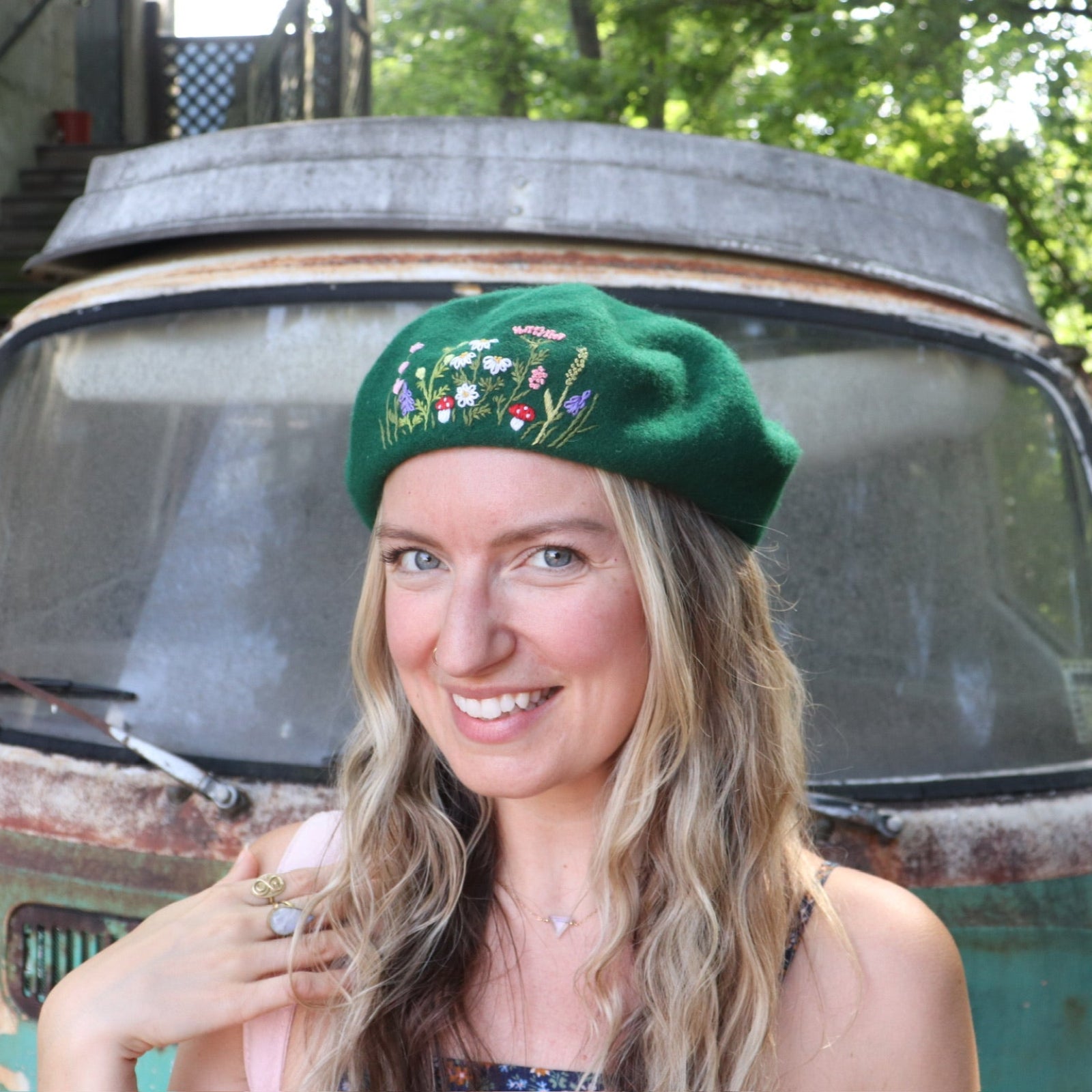 A woman wearing the green Hand-Embroidered Floral Soft Beret Stylish Hat with a navy floral dress.