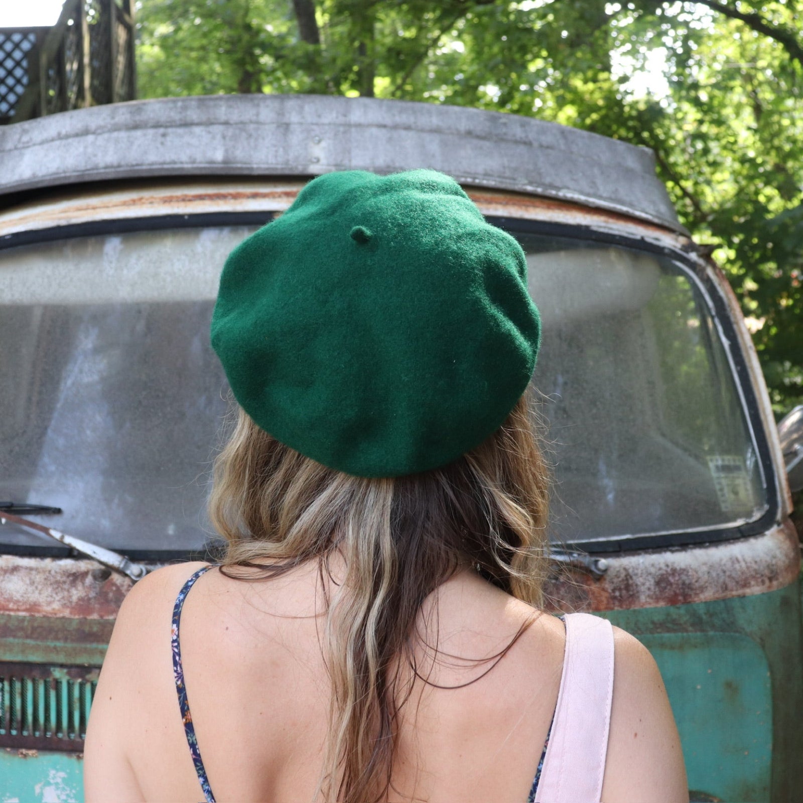 A woman wearing the green Hand-Embroidered Floral Soft Beret Stylish Hat with a navy floral dress, showing off the back of the hat.