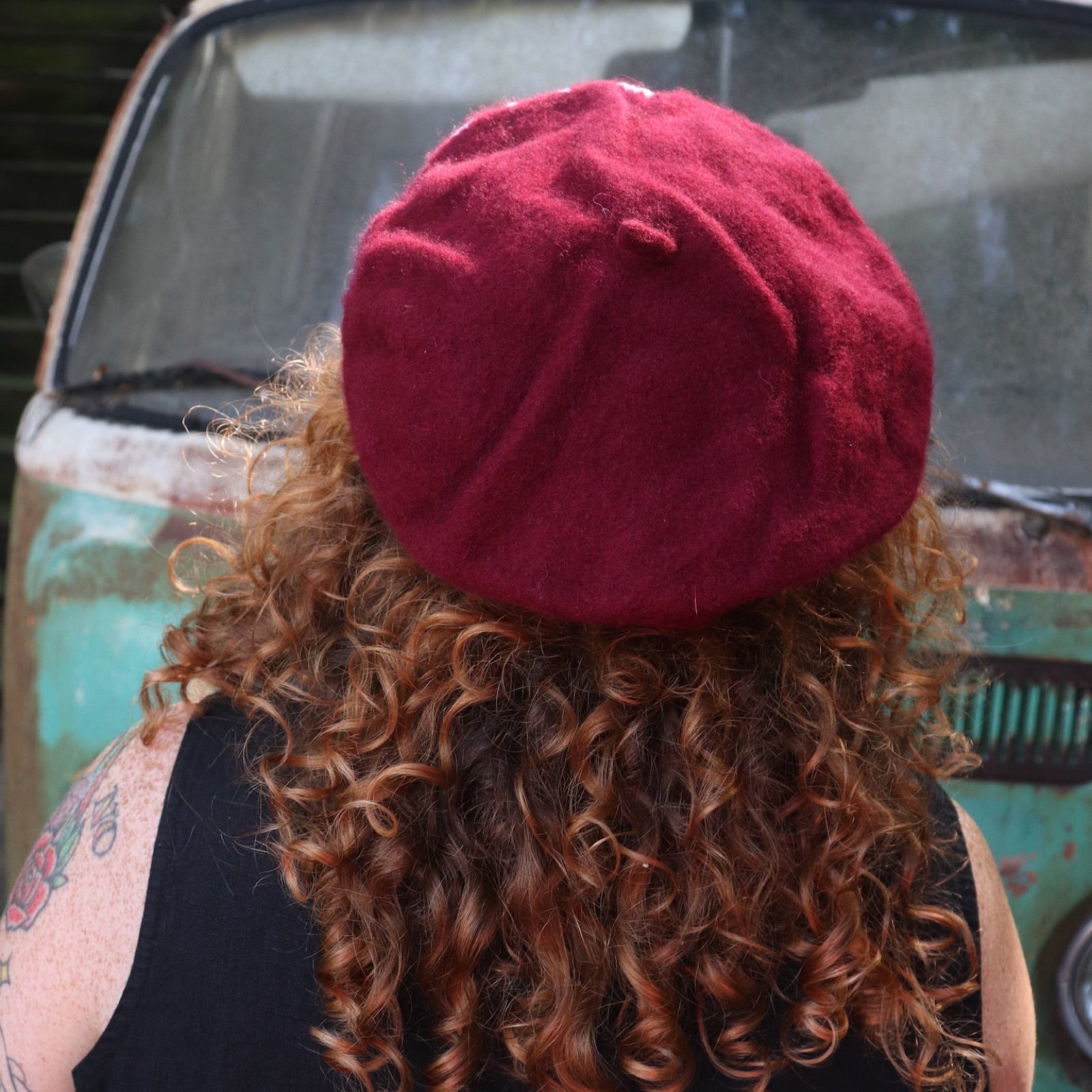 A woman wearing the red Hand-Embroidered Floral Soft Beret Stylish Hat with a black tank, showing off the back.
