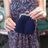 A woman in a navy floral dress holding the Deer Embroidered Navy Blue Coin Purse, showing off the back.