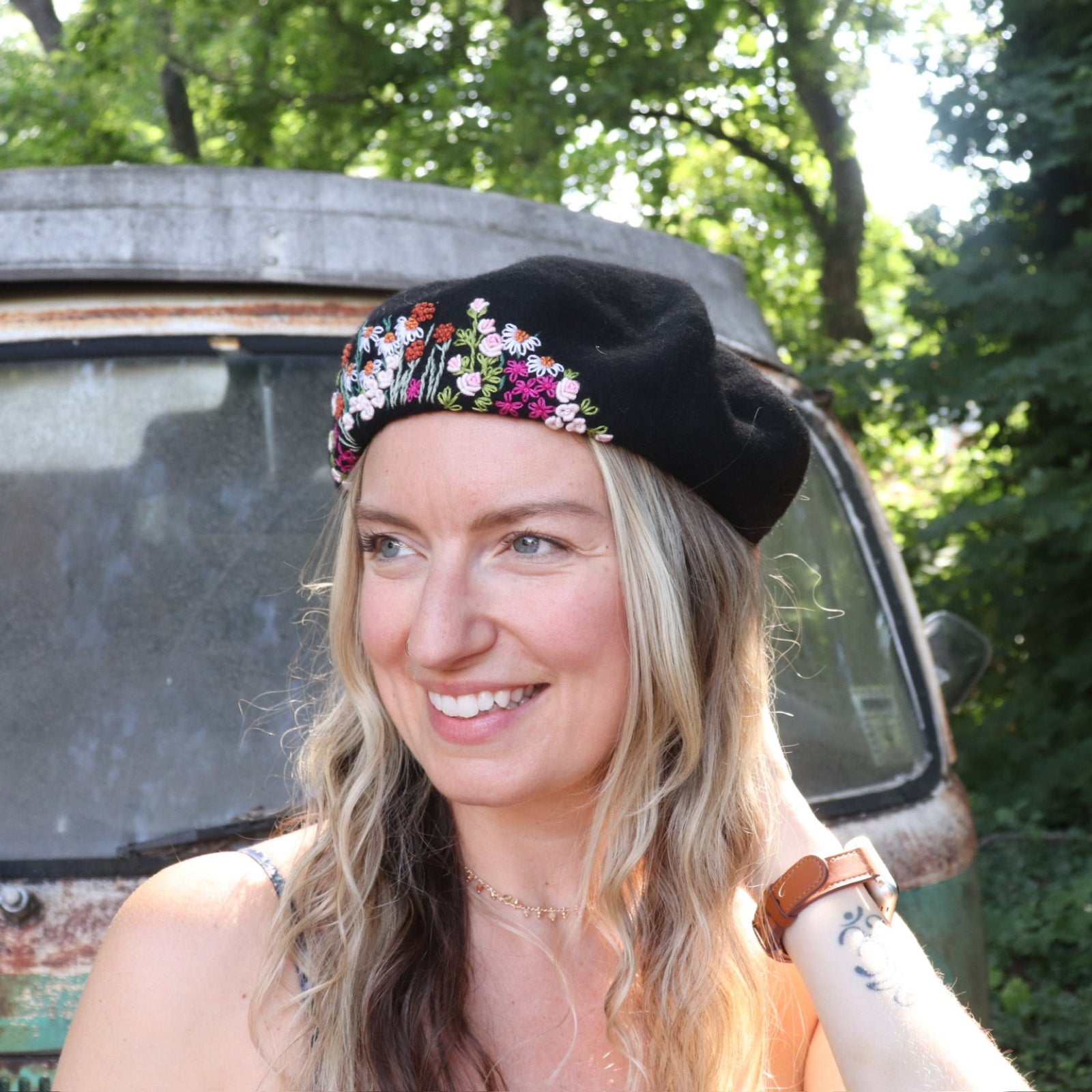 A woman wearing the black Hand-Embroidered Floral Soft Beret Stylish Hat with a navy floral dress.