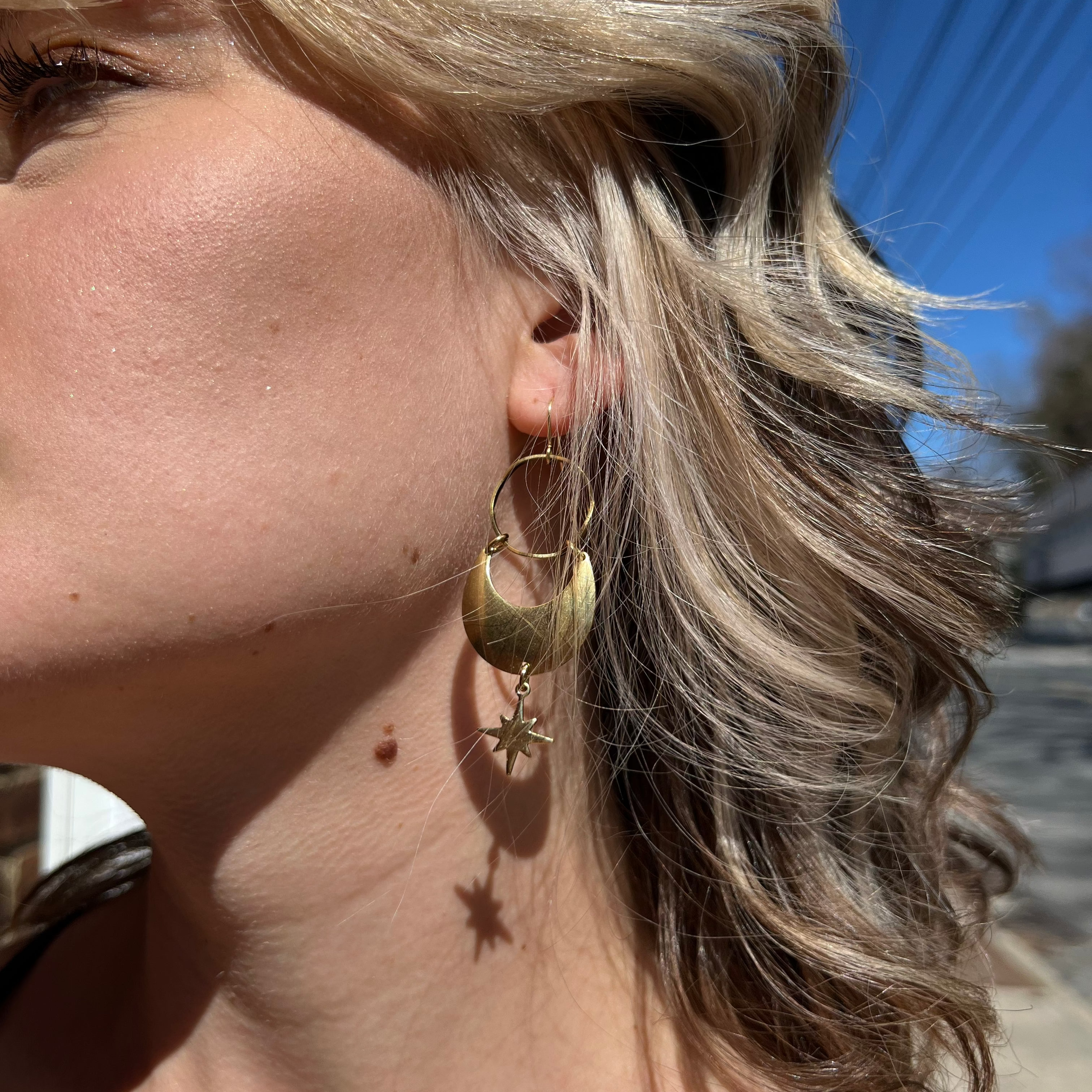 A woman wearing the Brass Star Dancer 2 inch. Earrings.