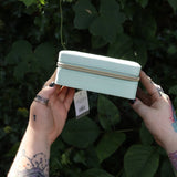 Someone holding the Once Upon a Time Travel Jewelry Organizer in front of greenery, showing off the side.