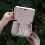 Someone holding the Once Upon a Time Travel Jewelry Organizer open in front of greenery, showing off the inside.