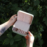 Someone holding the Once Upon a Time Travel Jewelry Organizer open in front of greenery, showing off the inside.