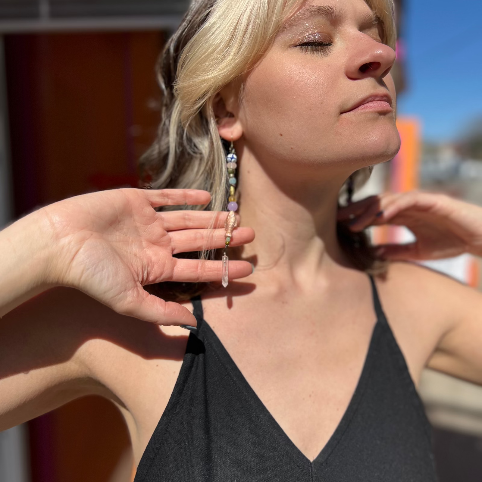 A woman wearing the Realm Earrings with a black dress.