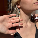 A woman wearing the Realm Earrings with a black dress.