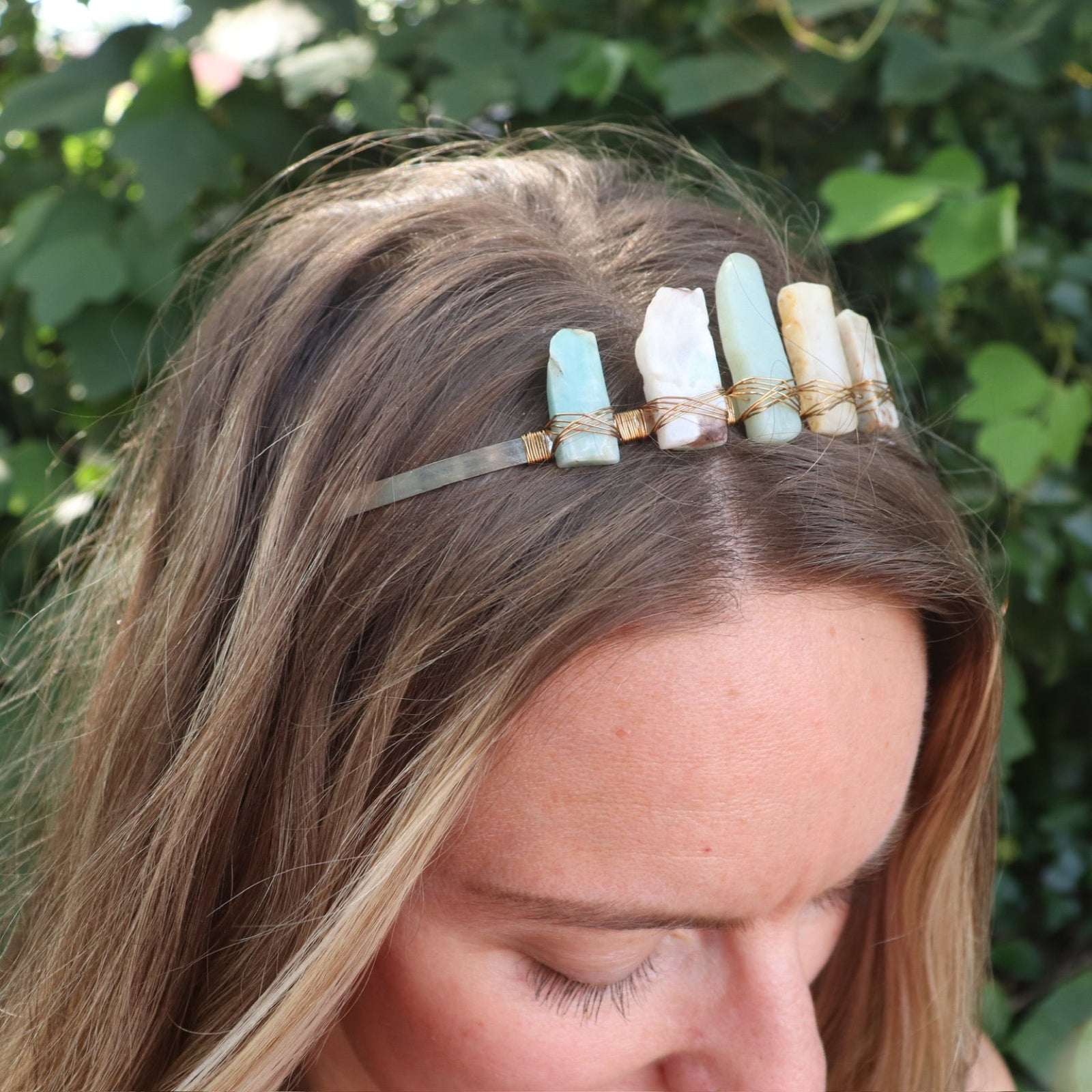 A woman wearing the Gemstone Tiara / Crown - Amazonite in front of greenery.