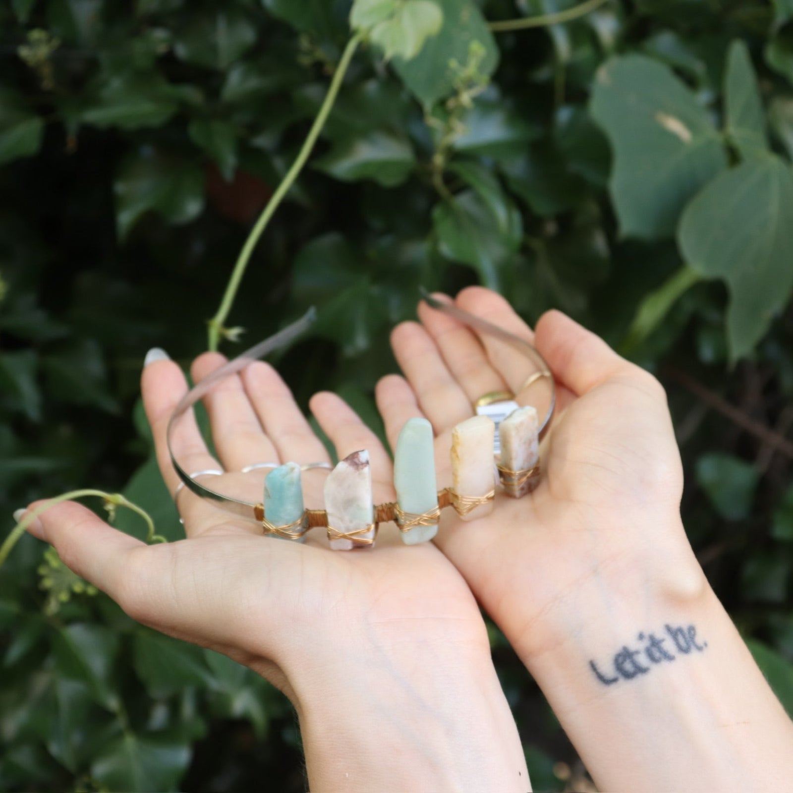 Someone holding the Gemstone Tiara / Crown - Amazonite in front of the greenery.