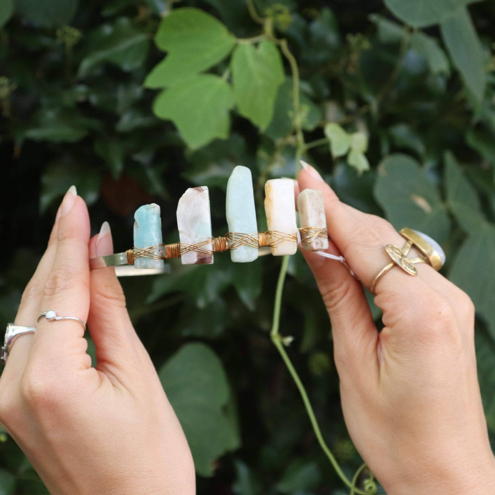 Someone holding the Gemstone Tiara / Crown - Amazonite in front of the greenery.