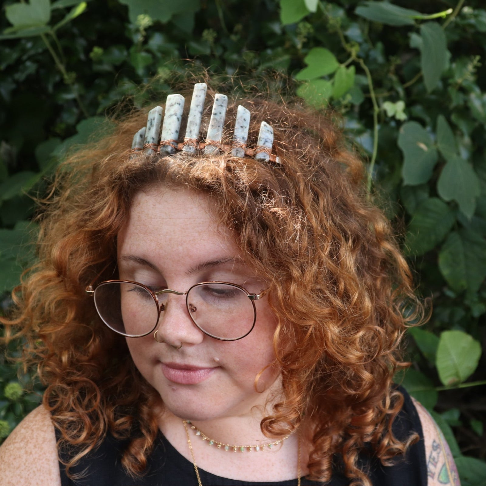 A woman wearing the Gemstone Tiara / Crown - Kiwi Jasper - Sesame in front of greenery.
