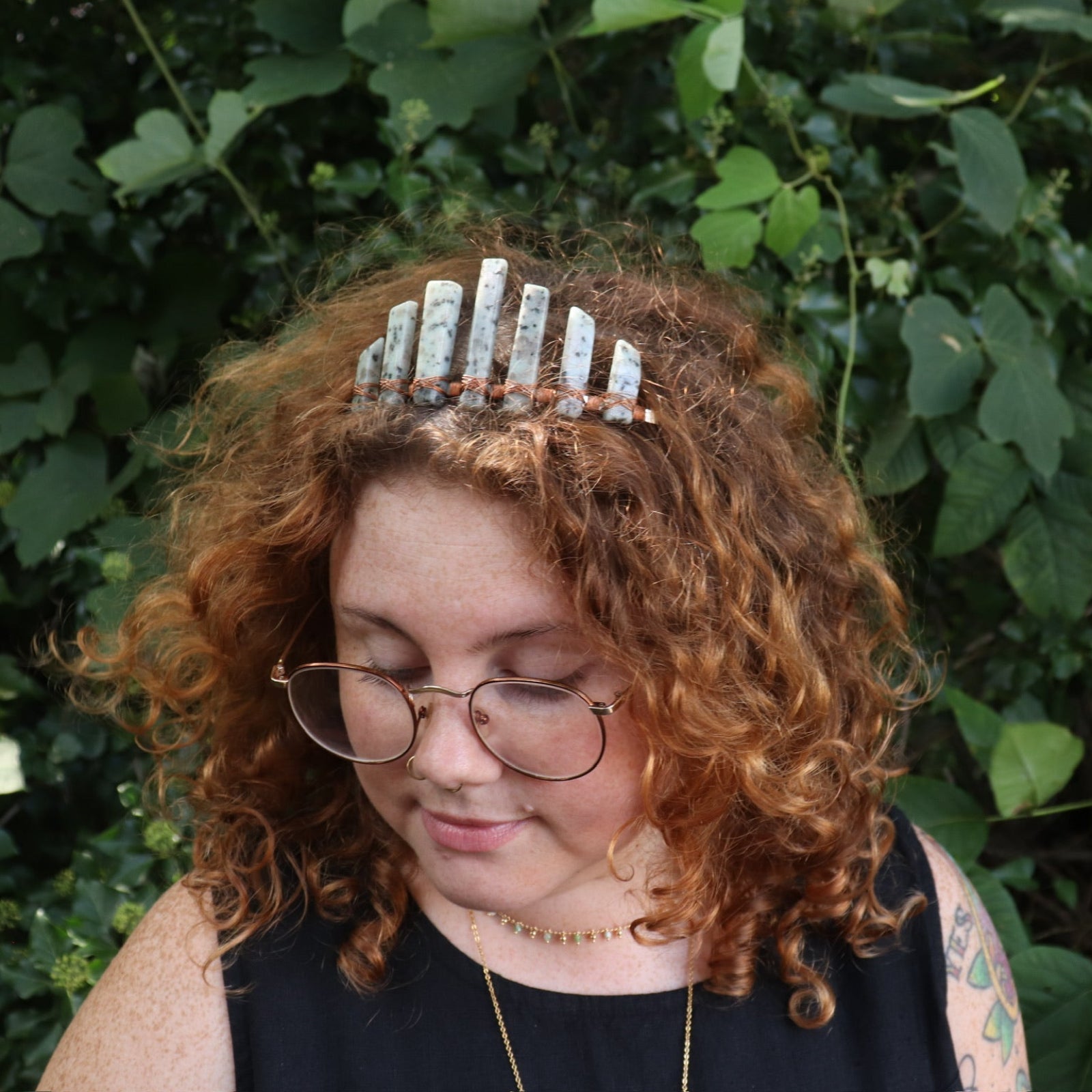 A woman wearing the Gemstone Tiara / Crown - Kiwi Jasper - Sesame in front of greenery.