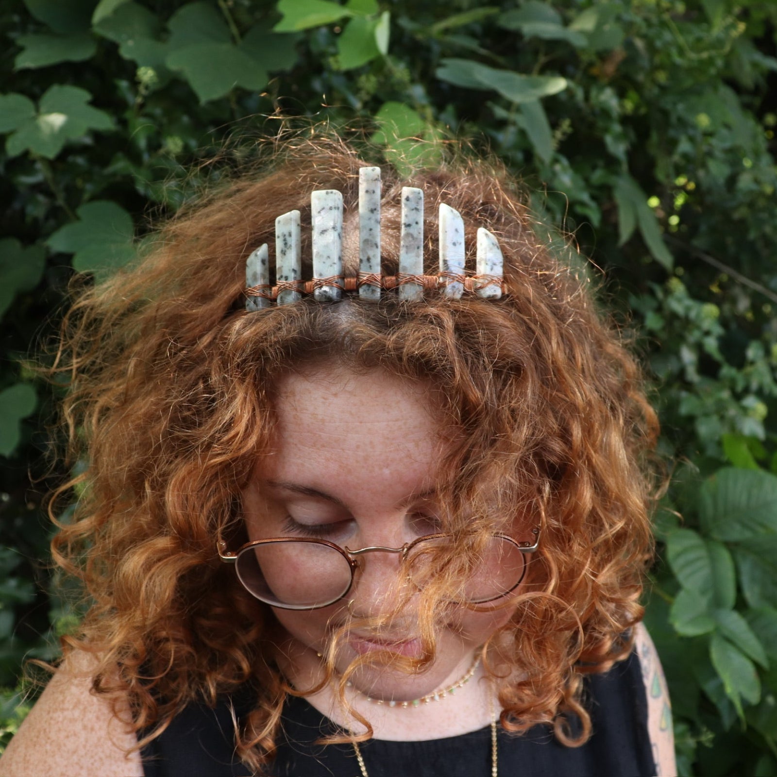 A woman wearing the Gemstone Tiara / Crown - Kiwi Jasper - Sesame in front of greenery.