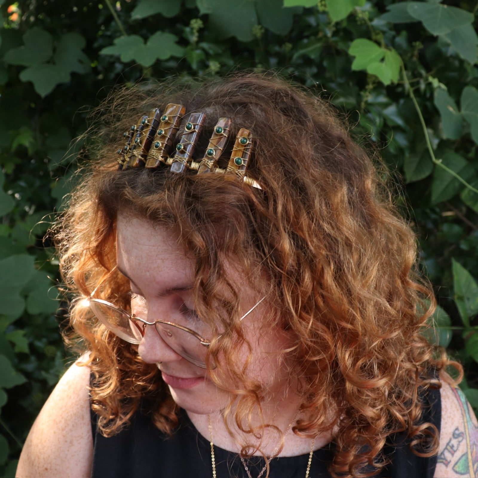 A woman wearing the Tigers Eye & Malachite Tiara in front of greenery.