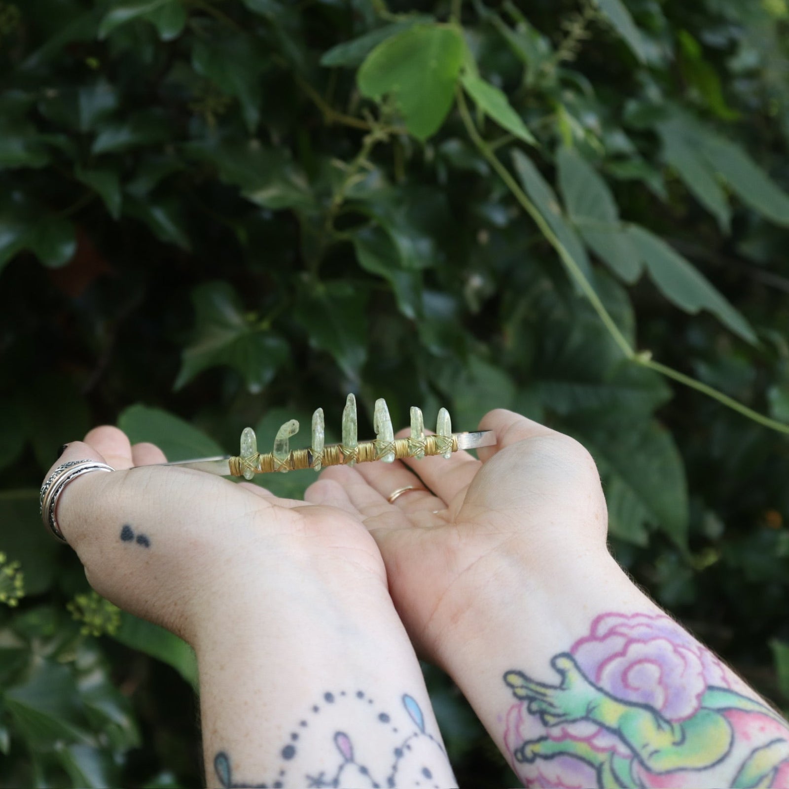 Someone holding the Fairy Crown / Celtic Tiara - Green Kyanite in front of greenery.