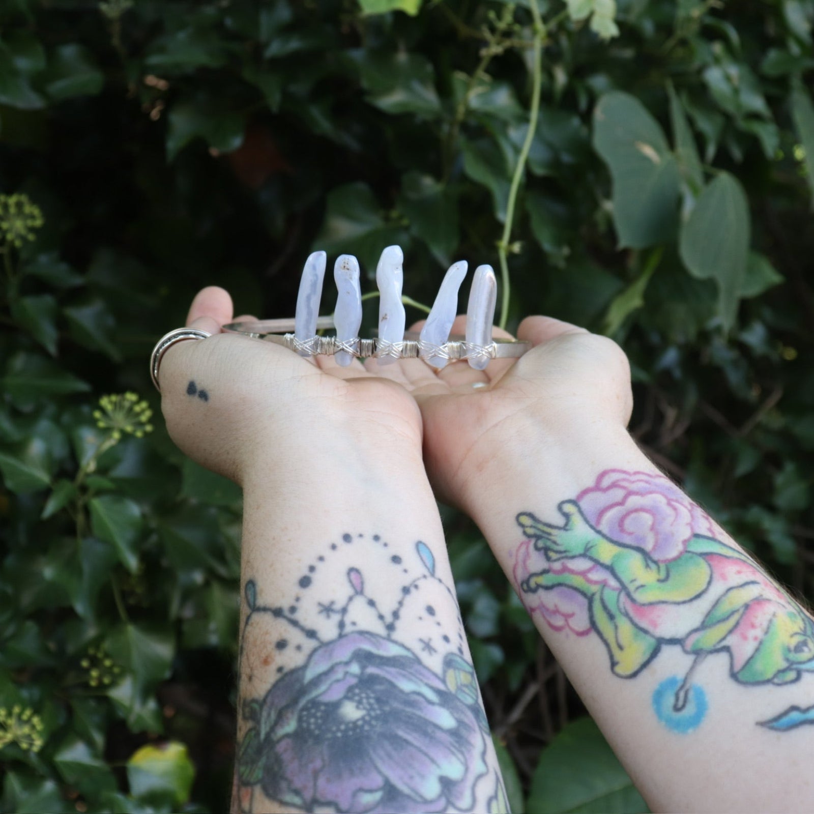 Someone holding the Fairy Crown / Celtic Tiara - Blue Chalcedony in front of greenery.